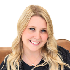 A headshot of Amanda Nevius, a smiling young woman with long blonde wavy hair, wearing a black top and a delicate silver necklace.