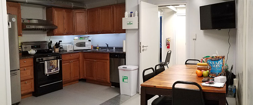 A kitchen and dining area in a modular unit featuring wooden cabinets, stainless steel appliances, and a wooden dining table with chairs.